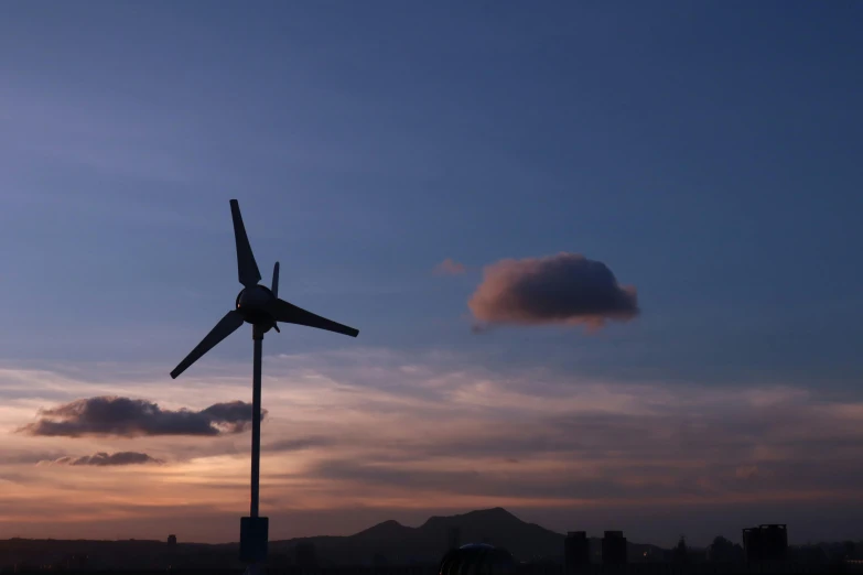 a wind turbine sitting on top of a metal pole, pexels contest winner, hurufiyya, evening sky, low quality photo, fan favorite, surrounding the city