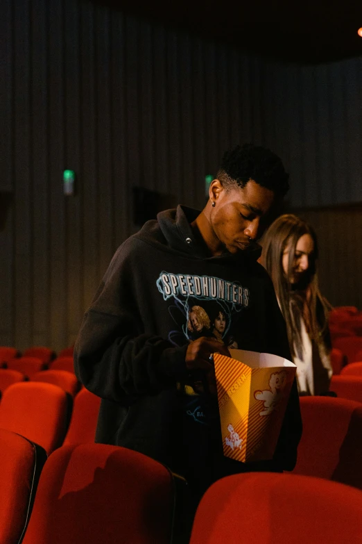 a group of people standing next to each other in a theater, snacks, 2 1 savage, [ theatrical ]