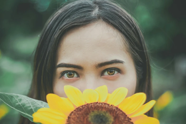 a woman holding a sunflower in front of her face, pexels contest winner, confident shaded eyes, a young asian woman, green and yellow tones, {perfect face}