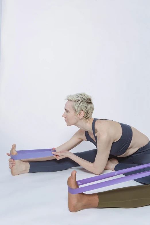 a woman doing a yoga pose with a resistance band, a picture, by Rachel Reckitt, dribble, figuration libre, purple tubes, low quality photo, profile image, close - up studio photo