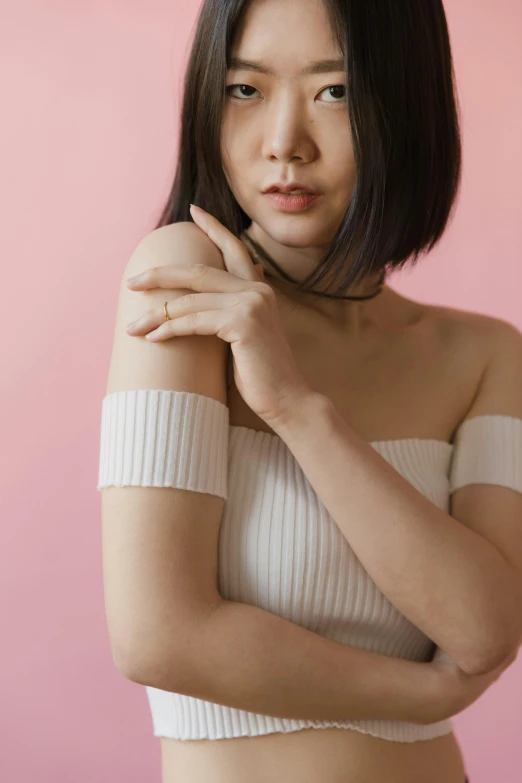a woman in a white top posing for a picture, an album cover, inspired by Ren Hang, trending on pexels, bandage on arms, smooth pink skin, elegant japanese woman, thoughtful