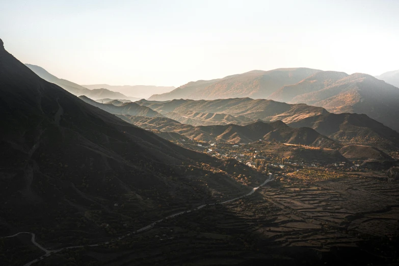 a view of a valley with mountains in the background, unsplash contest winner, les nabis, nekro petros afshar, distant town in valley and hills, late afternoon light, landslides