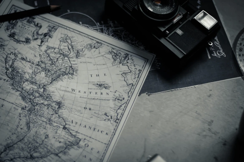 a black and white photo of a camera and a map, pexels contest winner, realism, battle map prop, papers on table, explorers, dark photo