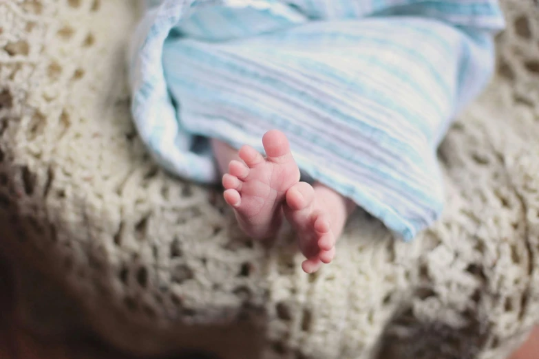 a close up of a baby's feet on a blanket, by Alice Mason, pexels, professionally post - processed, coloured, the birth, thumbnail