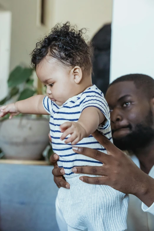 a man holding a baby in his arms, varying ethnicities, holding hand, looking confident, concerned