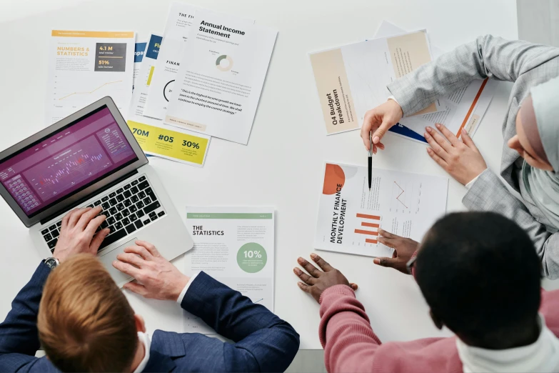 a group of people sitting around a table with laptops, pexels contest winner, analytical art, papers on table, infographics, professional branding, product introduction photo