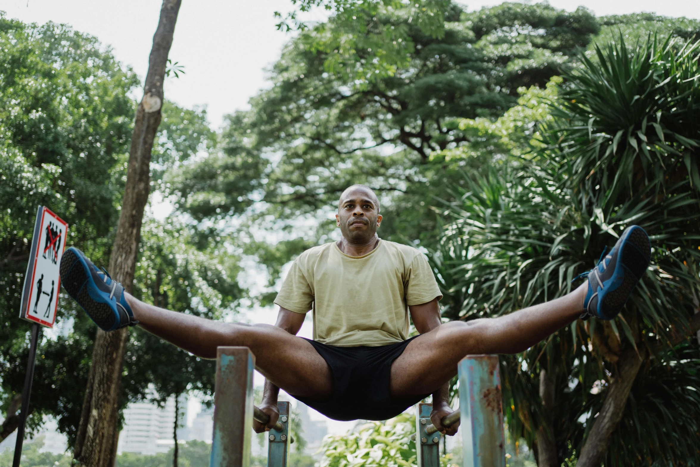 a man doing a handstand in a park, a portrait, by Jessie Alexandra Dick, pexels contest winner, sitting on a bench, malaysian, man is with black skin, symmetrical balance