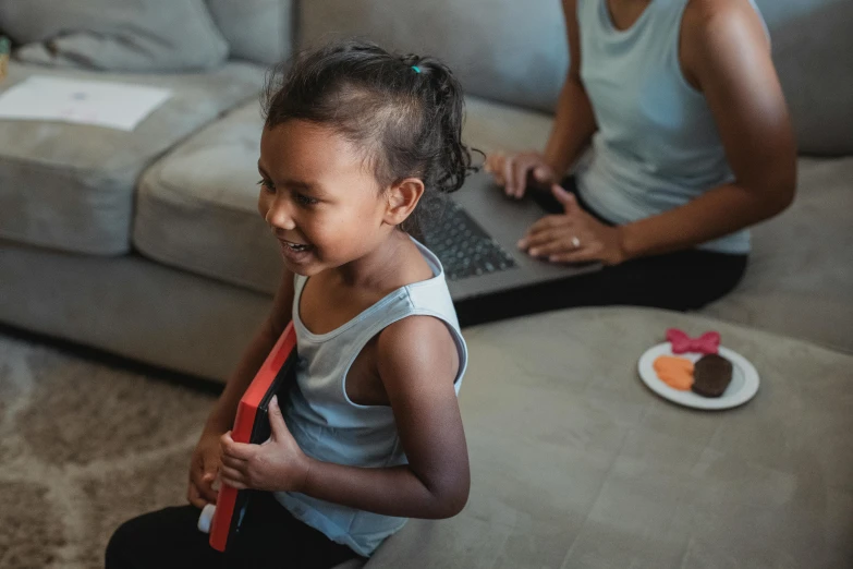 a little girl sitting on the floor in front of a laptop, pexels contest winner, happening, indian girl with brown skin, families playing, thumbnail, medium shot of two characters