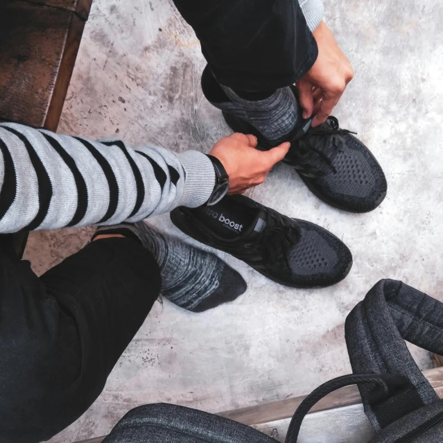 a close up of a person tying a pair of shoes, unsplash, yeezy collection, siblings, wearing black, pov photo