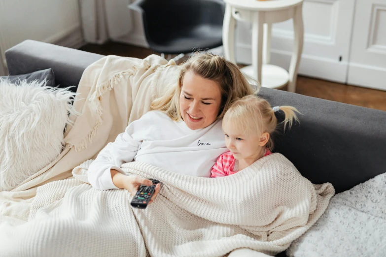 a woman sitting on top of a couch holding a baby, pexels contest winner, girls resting, watching tv, embroidered robes, happy girl