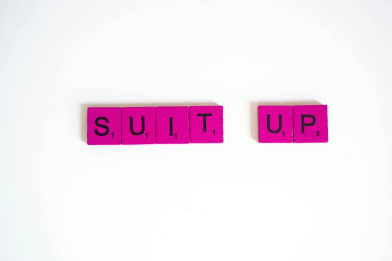 the word suit up spelled in scrabbles on a white surface, an album cover, inspired by Suzanne Duchamp-Crotti, unsplash, wearing a pink tux, no shirt under the vest, photo taken from the ground, sulfur