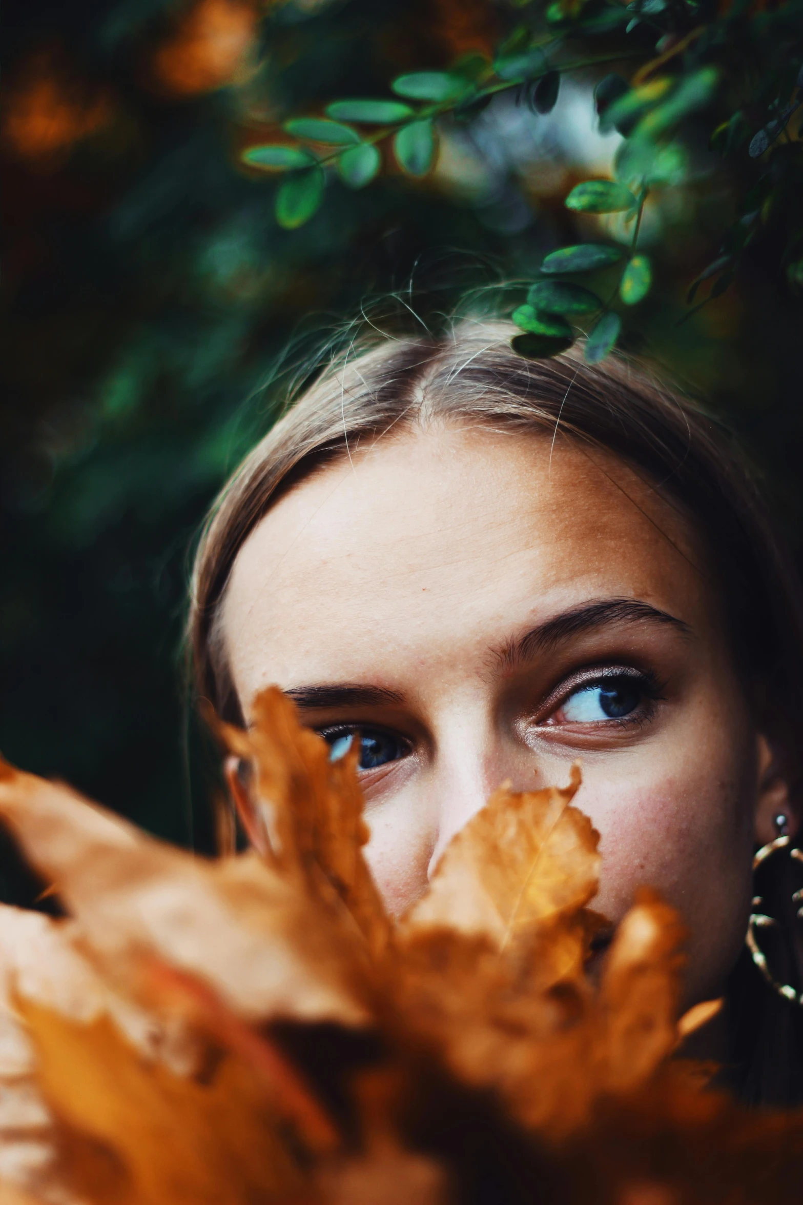 a woman holding a leaf in front of her face, trending on pexels, blonde hair and large eyes, photo of a model, brown flowers, full frame image