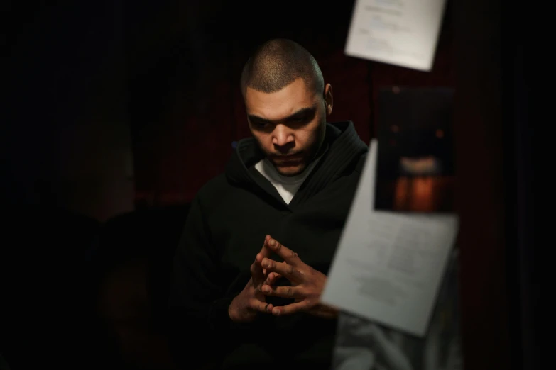 a man standing in front of a bunch of papers, an album cover, pexels contest winner, group of people in a dark room, riyahd cassiem, pensive expression, [ theatrical ]