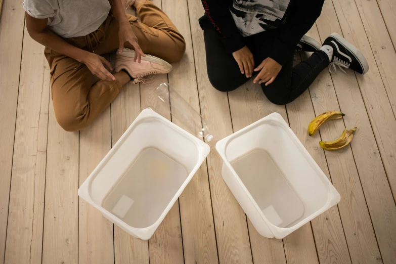 a couple of people sitting on top of a wooden floor, inspired by Leandro Erlich, unsplash, process art, fixing a leaking sink, beakers, ikea, high quality photo