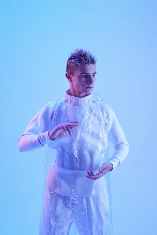 a man dressed in white standing in front of a blue background, inspired by Nikolaj Abraham Abildgaard, holography, wearing futuristic clothing, justin bieber, covered in circuitry, genderless