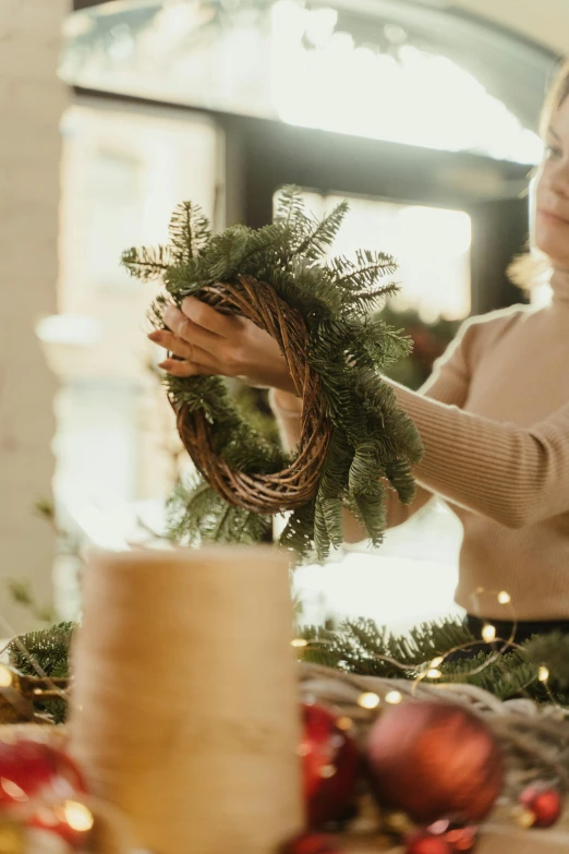 a woman putting a wreath on top of a table, pexels, folk art, natural lights, transforming, with detailed, cardboard