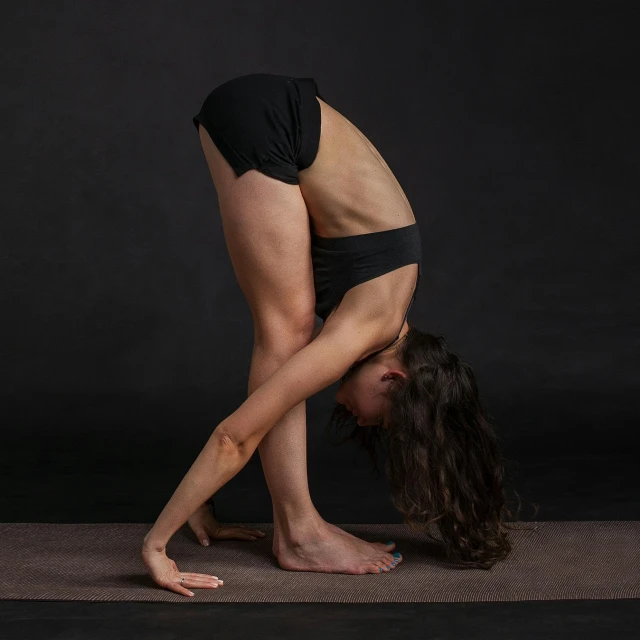 a woman doing a handstand pose on a yoga mat, by Carey Morris, pexels contest winner, renaissance, standing with a black background, bent over, full body picture, women full body