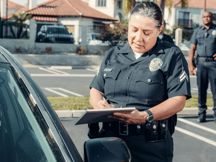 a woman in a police uniform standing next to a car, pexels contest winner, happening, writing on a clipboard, california;, diverse, thumbnail