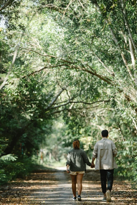 a man and a woman walking down a path in the woods, by Elizabeth Durack, unsplash, madagascar, taken with kodak portra, lush green, romance