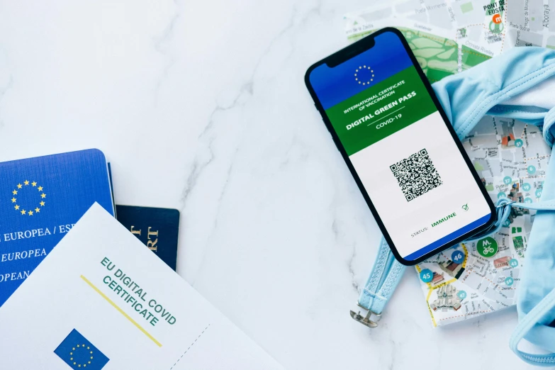 a phone sitting on top of a table next to a passport, by Julia Pishtar, pexels contest winner, green and blue color scheme, european union, 🦩🪐🐞👩🏻🦳, smartphone displays qr code