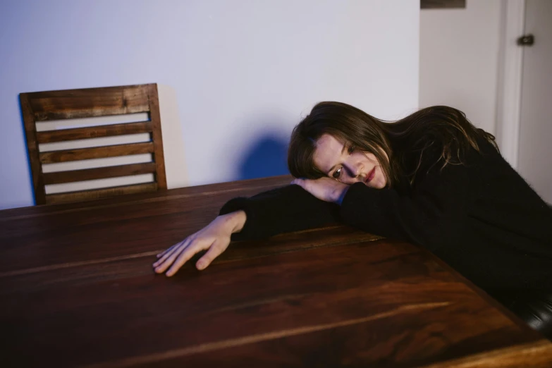 a woman laying on top of a wooden table, unsplash, realism, beautiful taissa farmiga, exasperated, studio shot, cynthwave