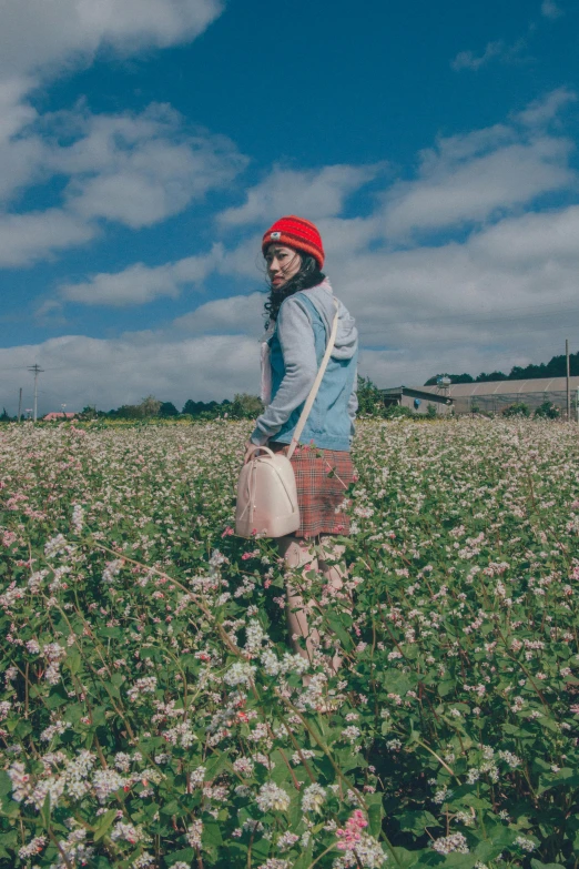 a woman standing in a field of flowers, an album cover, unsplash, color field, wearing a red backwards cap, japanesse farmer, wearing strawberry backpack, cinematic outfit photo