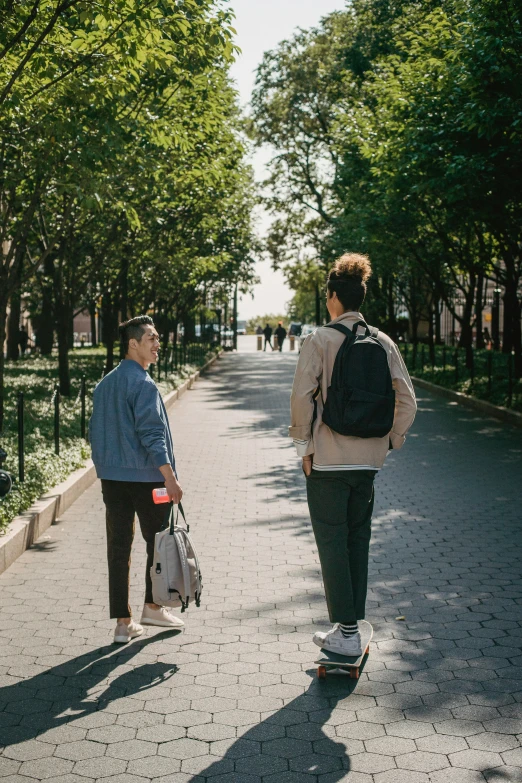 a couple of people walking down a sidewalk, a man wearing a backpack, in a square, brooklyn, college