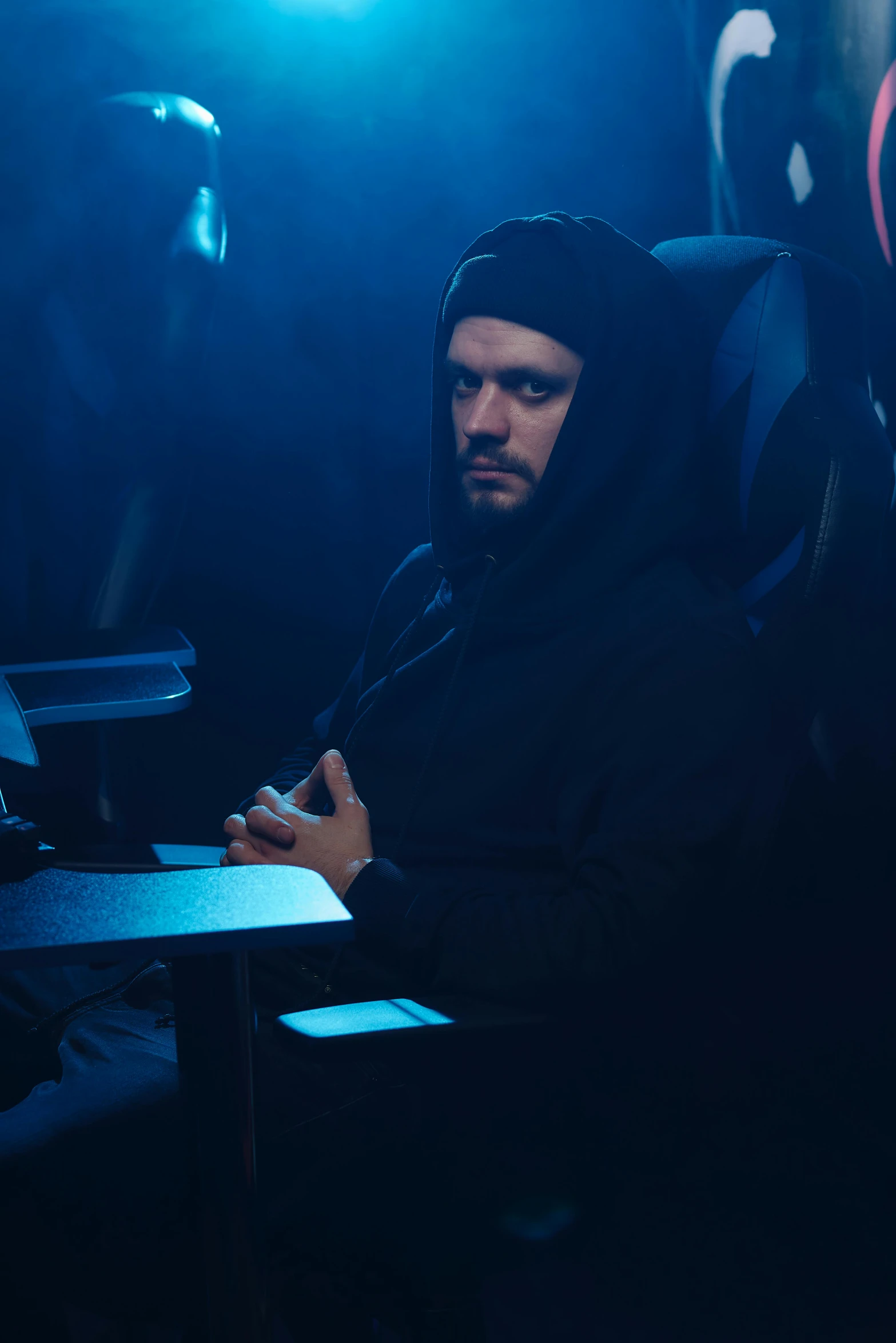 a man sitting at a table in a dark room, wearing sith hood, mrbeast, on an icy throne, looking distracted and awkward