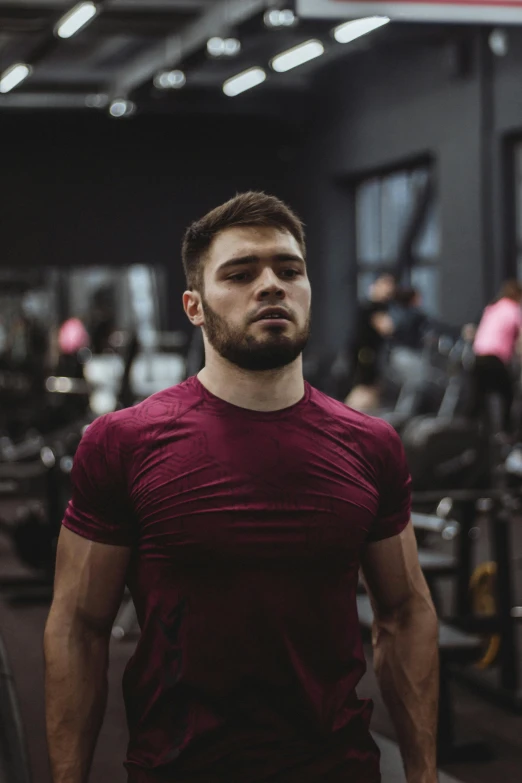 a man standing in a gym holding a barbell, by Adam Marczyński, khabib, maroon, light stubble with red shirt, athletic build