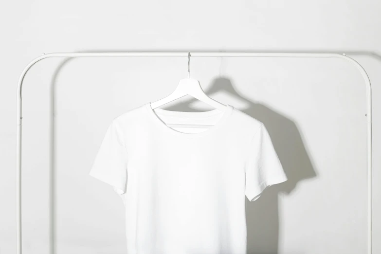 a white t - shirt hanging on a clothes rack, an ambient occlusion render, by Nicolette Macnamara, trending on unsplash, minimalism, collar around neck, white studio background, instagram post, wearing white leotard