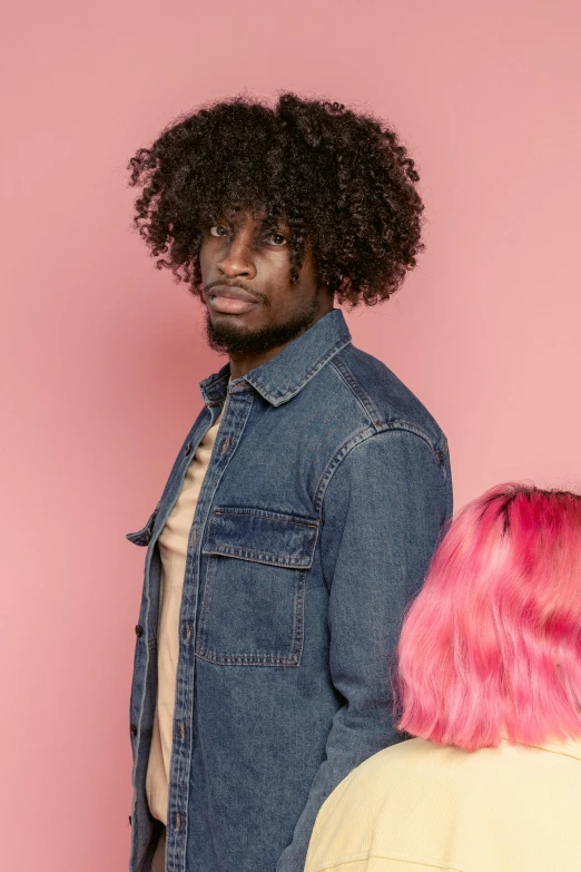 a man standing next to a woman with pink hair, an album cover, inspired by Theo Constanté, trending on pexels, denim jacket, wig, ( ( dark skin ) ), male model