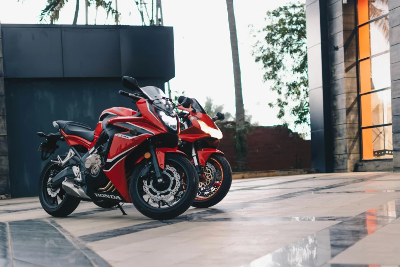 a red motorcycle parked in front of a building, inspired by Hiroshi Honda, pexels contest winner, twins, silver red, avatar image, indonesia