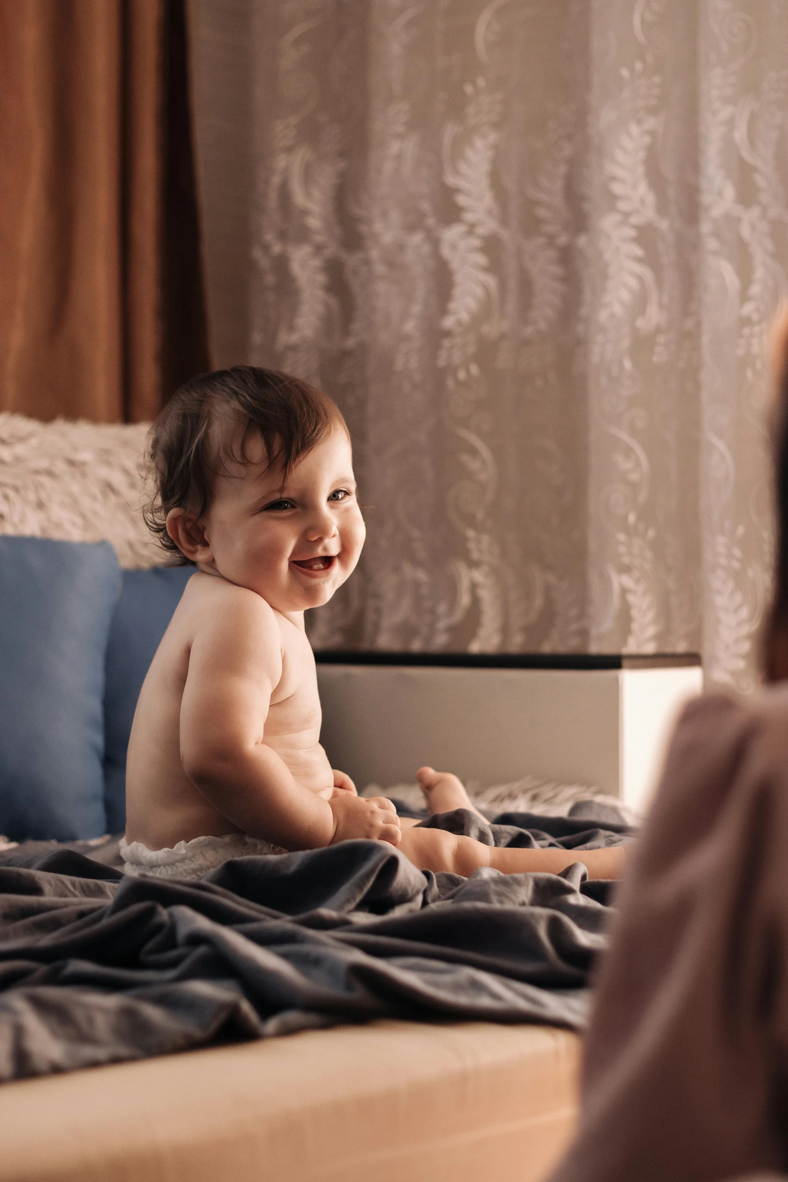 a baby sitting on top of a bed next to a woman, admiring her own reflection, tv commercial, happy cozy feelings, zoomed in