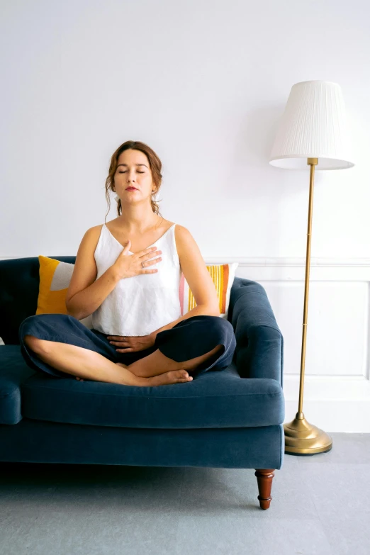 a woman sitting on top of a blue couch, a statue, unsplash, yoga meditation pose, pointé pose;pursed lips, square, full product shot