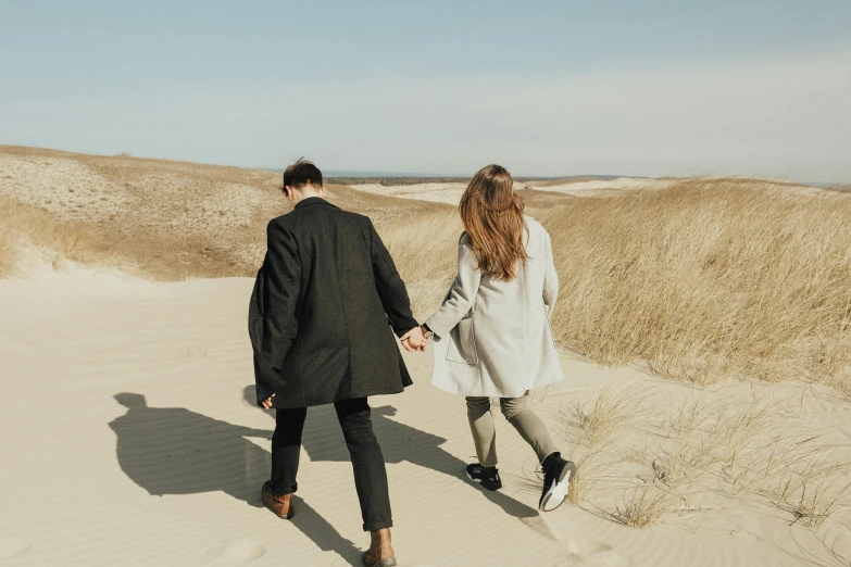 a man and a woman walking in the sand, pexels contest winner, hammershøi, well - dressed, thumbnail, background image