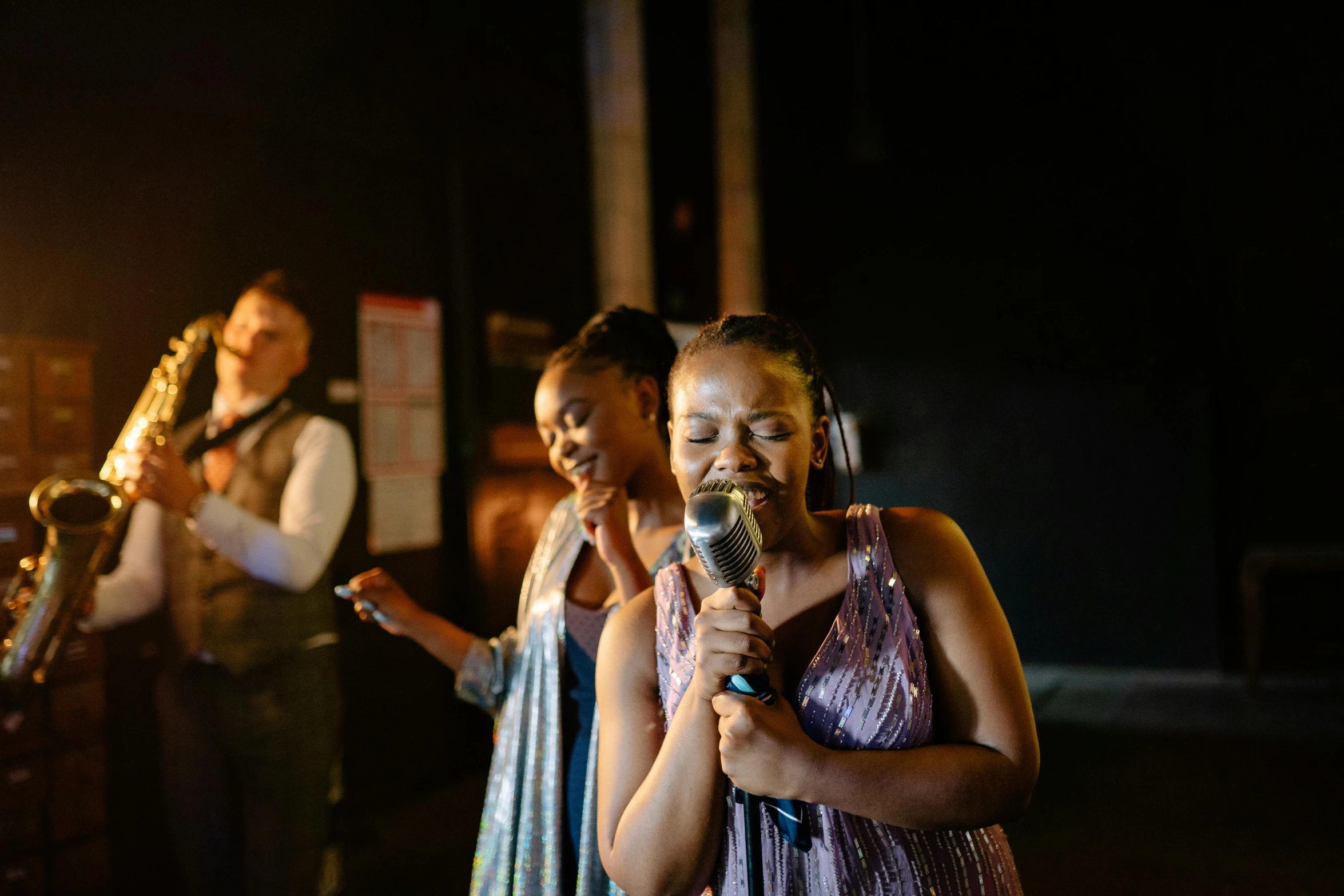 a group of women standing next to each other holding microphones, by Lee Loughridge, happening, 3 actors on stage, soul singer, smooth in _ the background, high quality photo