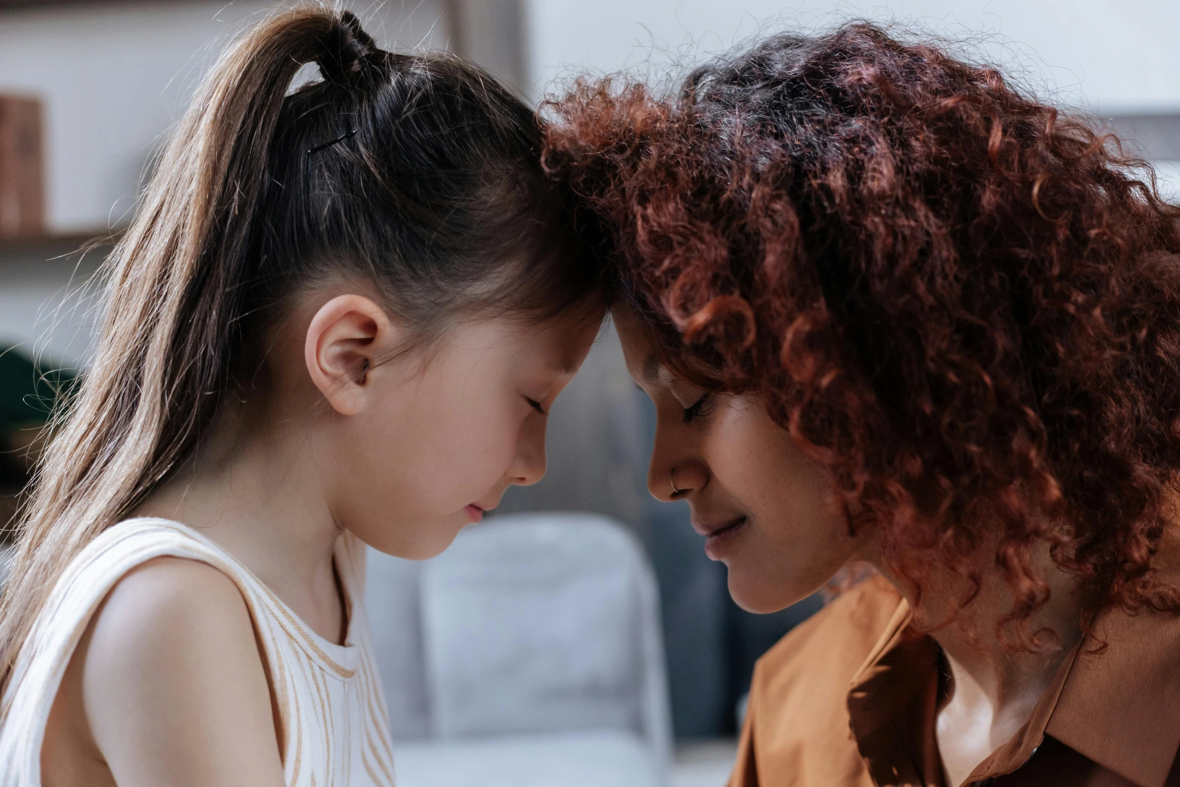 a couple of young girls standing next to each other, trending on pexels, bedhead, te pae, facing each other, with a kid