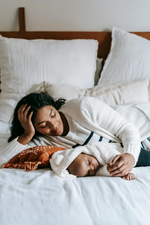 a woman laying on top of a bed next to pillows, by Carey Morris, pexels contest winner, renaissance, with a kid, ashteroth, caring fatherly wide forehead, profile image