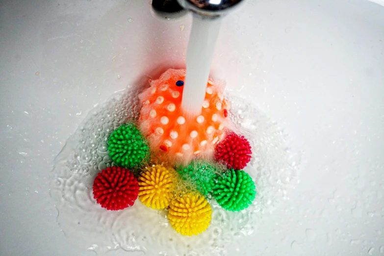 a faucet spouting water into a sink filled with colorful balls, a stipple, pexels, orange fluffy spines, wearing spiky, brain in a vat, high angle close up shot