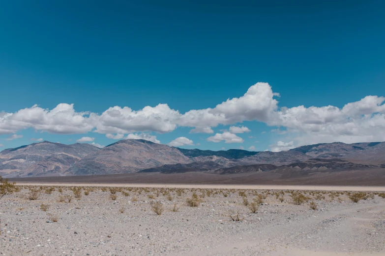 a desert landscape with mountains in the distance, by Ryan Pancoast, unsplash contest winner, blue sky and white clouds, background image, sparsely populated, chemistry