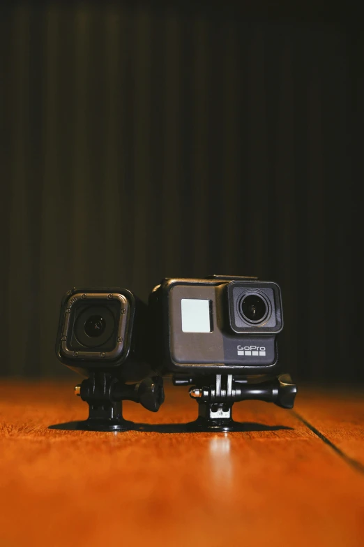 two gopro cameras sitting on top of a wooden table, by Carey Morris, unsplash, square, panoramic anamorphic, black, kit