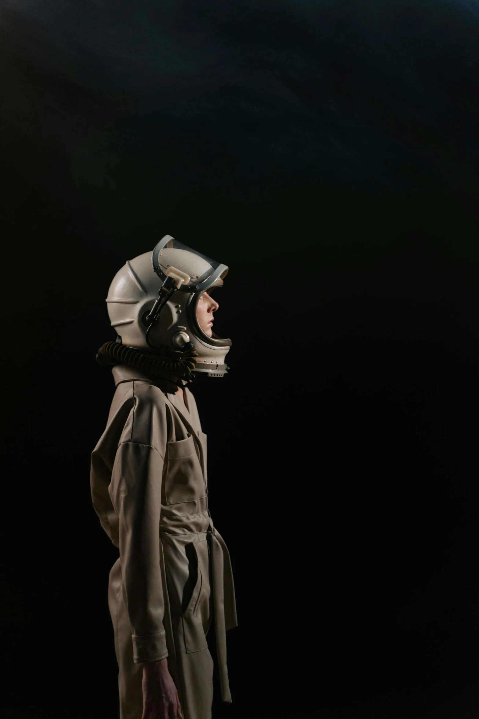 a man in a space suit standing in the dark, by Alison Geissler, photorealism, grey, canvas, 70's jetfighter pilot, photographic hyperrealism