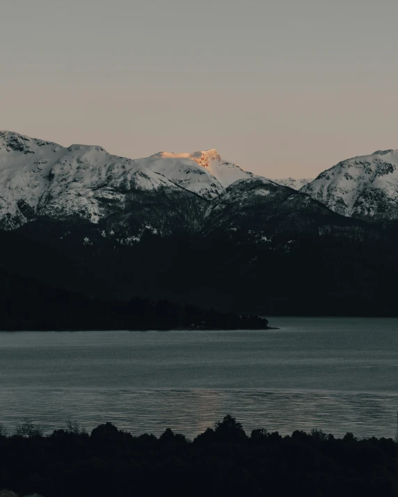 a large body of water with mountains in the background, unsplash contest winner, late evening, with snow on its peak, trending on vsco, soft lighting from above