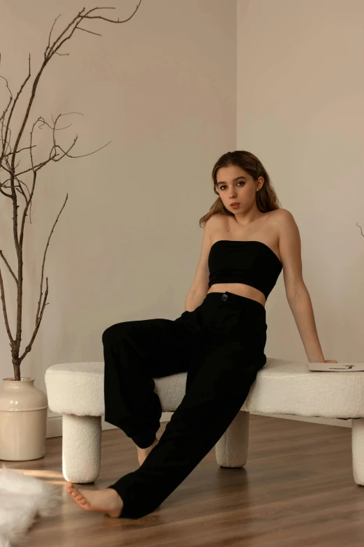 a woman sitting on a white bench in a room, by Robbie Trevino, baggy black pants, portrait sophie mudd, official store photo, round-cropped