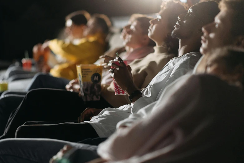 a group of people sitting in a row watching a movie, trending on pexels, movie promotional image, portrait photo, [ theatrical ]