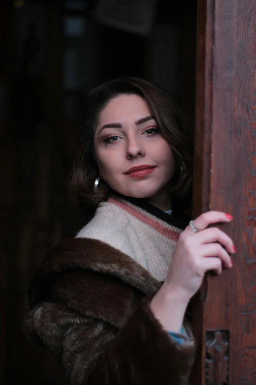 a woman in a fur coat leaning against a door, a portrait, inspired by Elsa Bleda, pexels contest winner, renaissance, young beautiful amouranth, dressed like in the 1940s, beautiful iranian woman, headshot