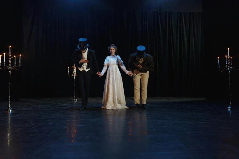 a group of people standing on top of a stage, victorian style costume, walking towards the camera, 3 heads, in a black room