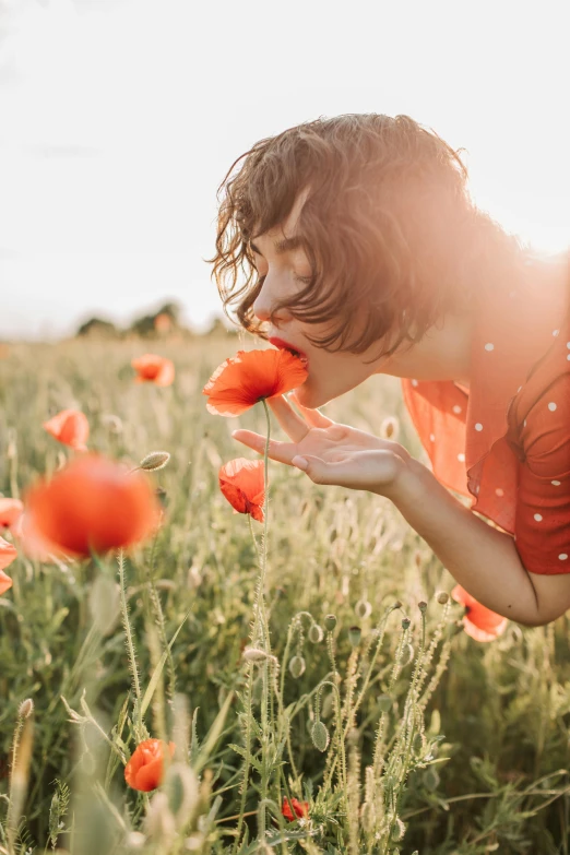 a woman blowing a flower in a field, pexels contest winner, light red and orange mood, licking out, instagram post, grazing