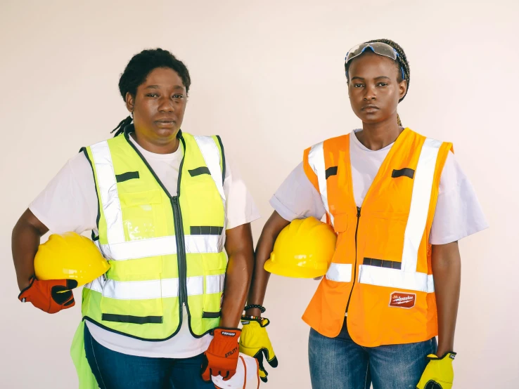 a couple of women standing next to each other, wearing hi vis clothing, maria borges, thumbnail, full image