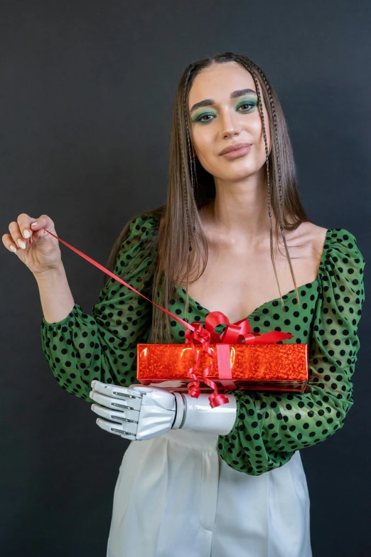 a woman in a green shirt holding a red present, by Julia Pishtar, robot hands, portrait emily ratajkowski, detailed product image, wearing silver dress